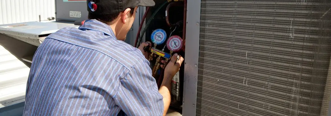 HVAC technician servicing a condenser unit in Marana